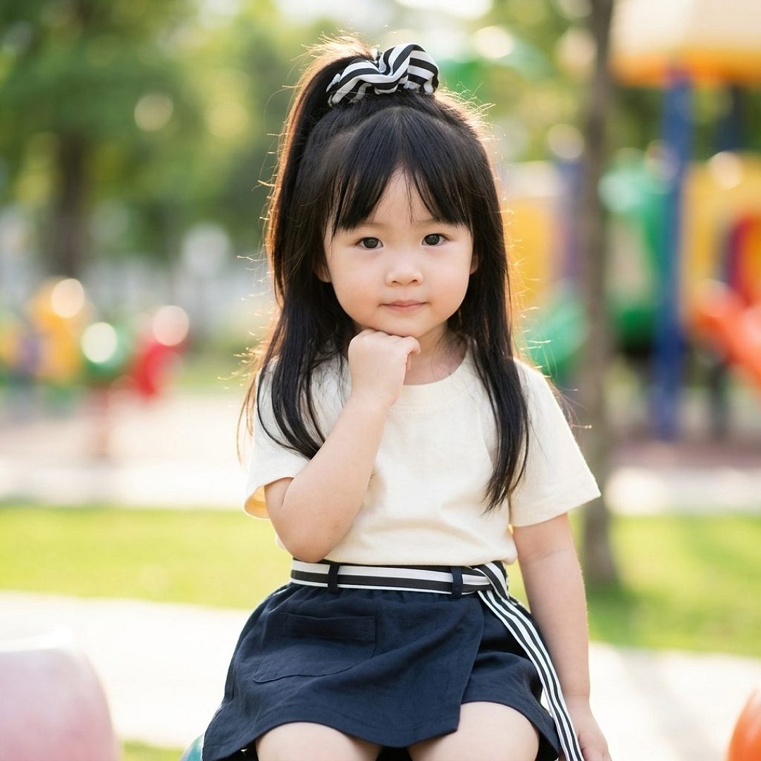 Anak perempuan lucu pakai setelan baju rok di taman